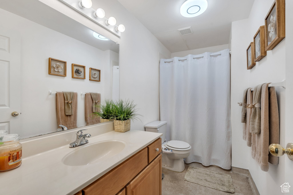 Bathroom featuring toilet, vanity, and a shower with shower curtain