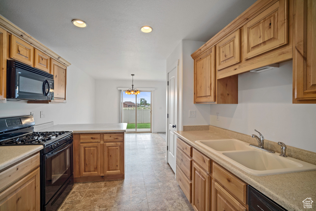 Kitchen featuring black appliances, a sink, light countertops, recessed lighting, and a peninsula