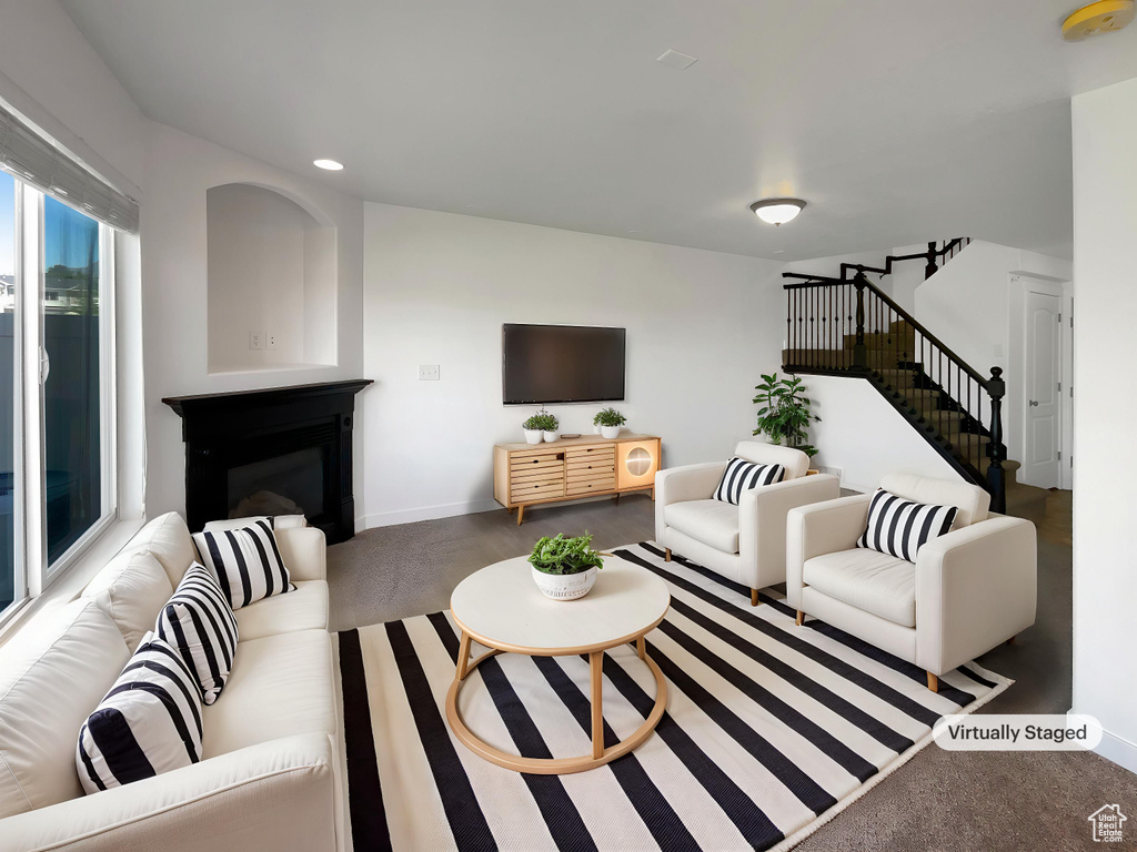Living area featuring stairs, a glass covered fireplace, recessed lighting, and baseboards