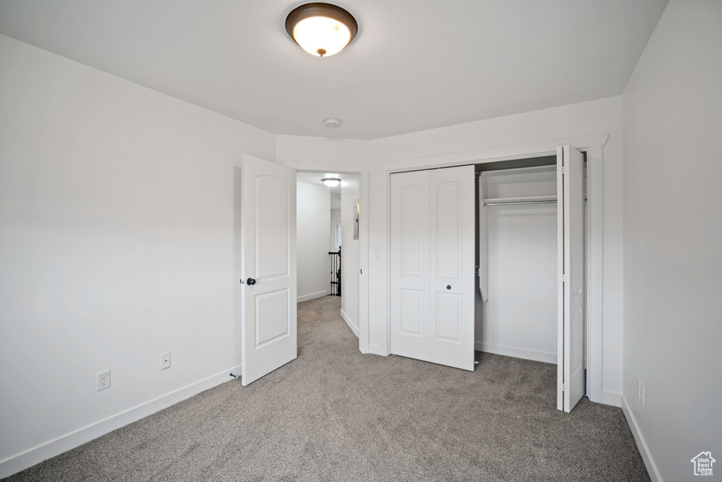 Unfurnished bedroom featuring carpet floors, baseboards, and a closet