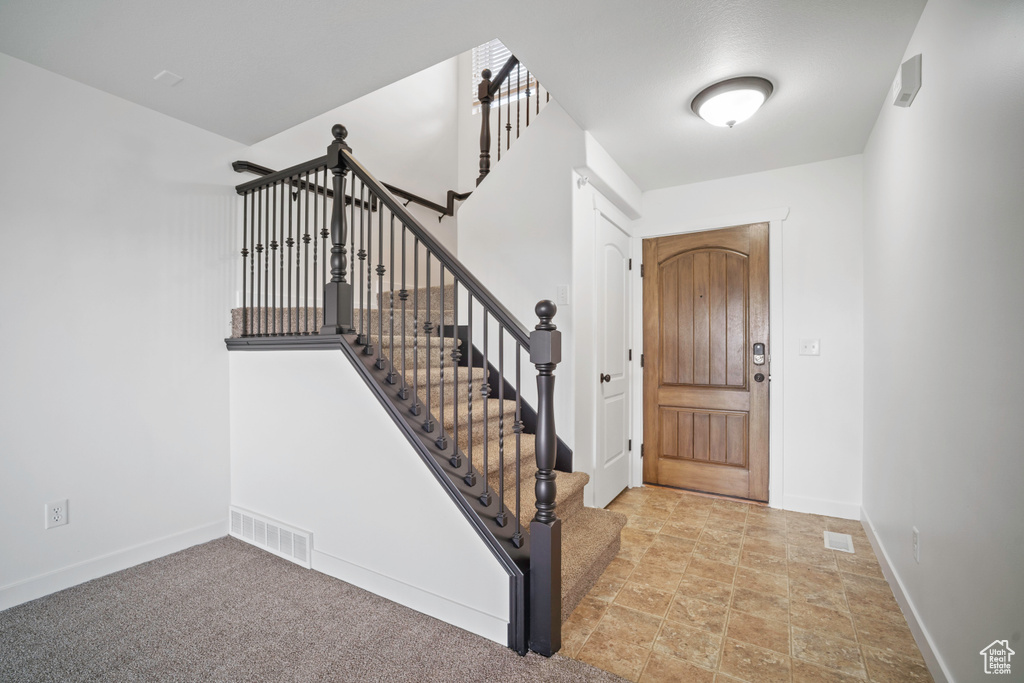 Entrance foyer with baseboards, stairs, and stone finish floors