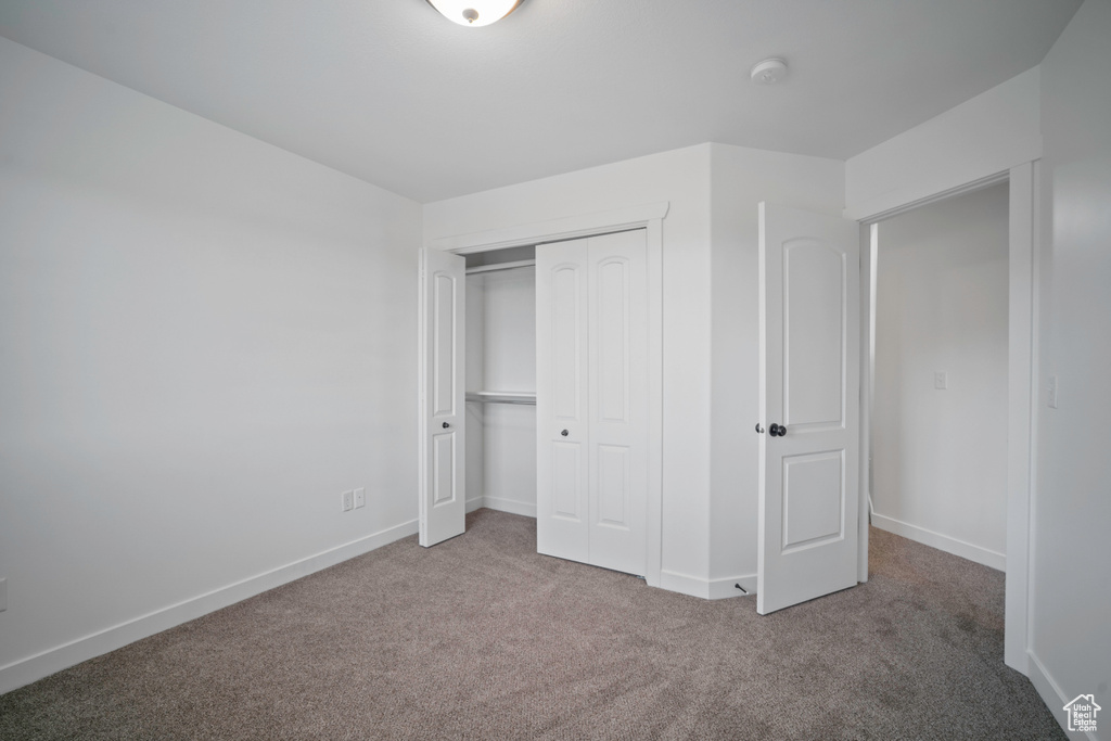 Unfurnished bedroom with carpet, a closet, and baseboards
