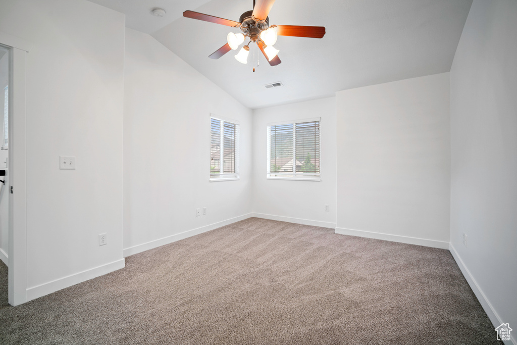 Carpeted spare room featuring lofted ceiling, a ceiling fan, baseboards, and a smoke detector