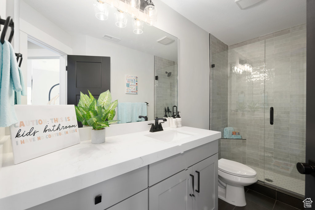 Bathroom with tile patterned floors, a shower stall, vanity, and toilet