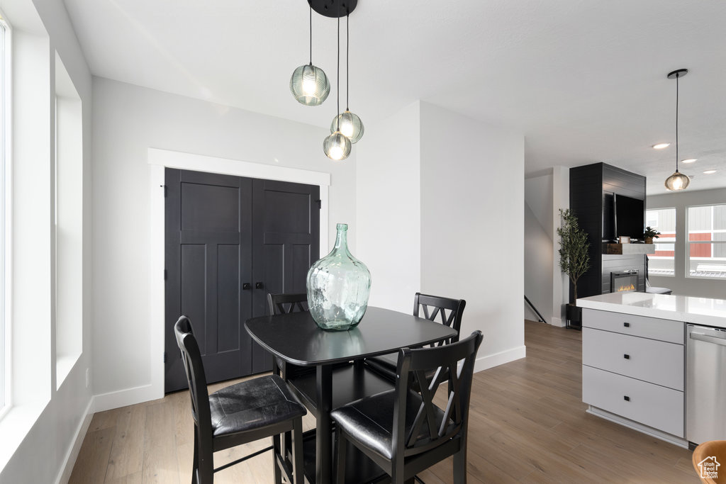 Dining room with baseboards, light wood-style floors, recessed lighting, and a large fireplace