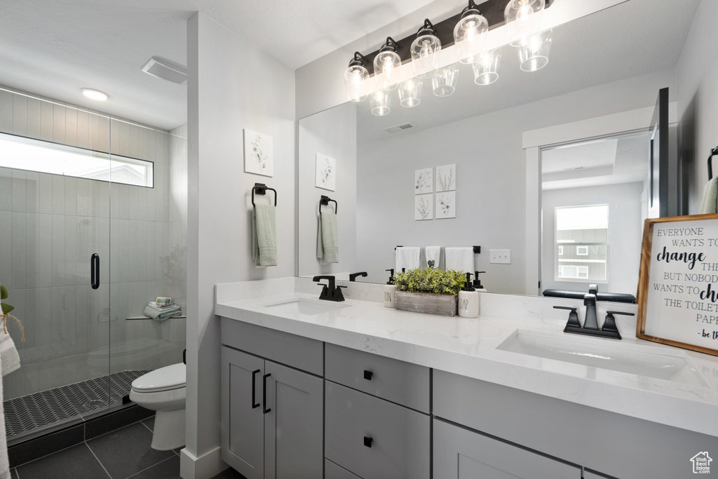 Bathroom featuring plenty of natural light, toilet, a shower stall, and tile patterned flooring