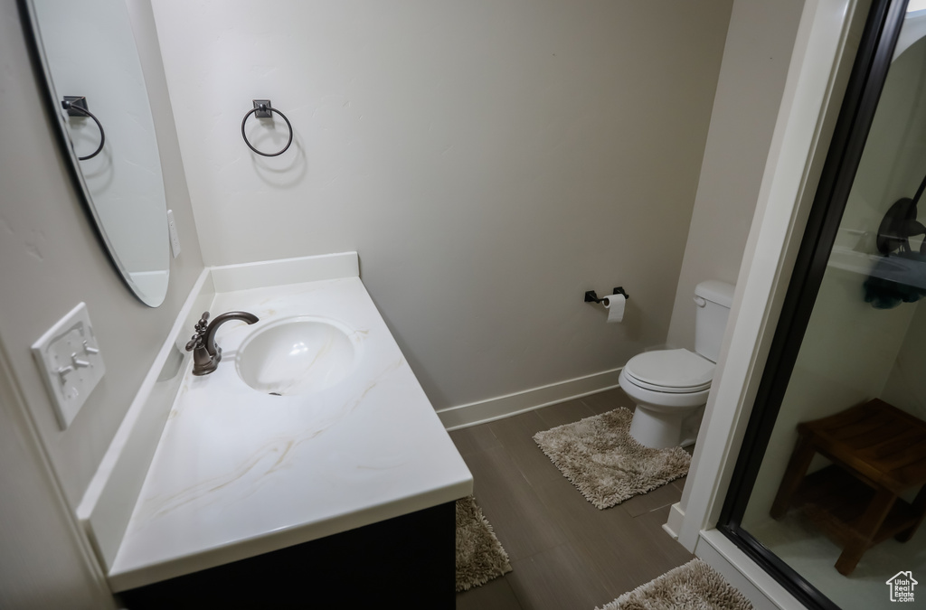 Bathroom featuring vanity, toilet, a shower stall, wood finished floors, and baseboards