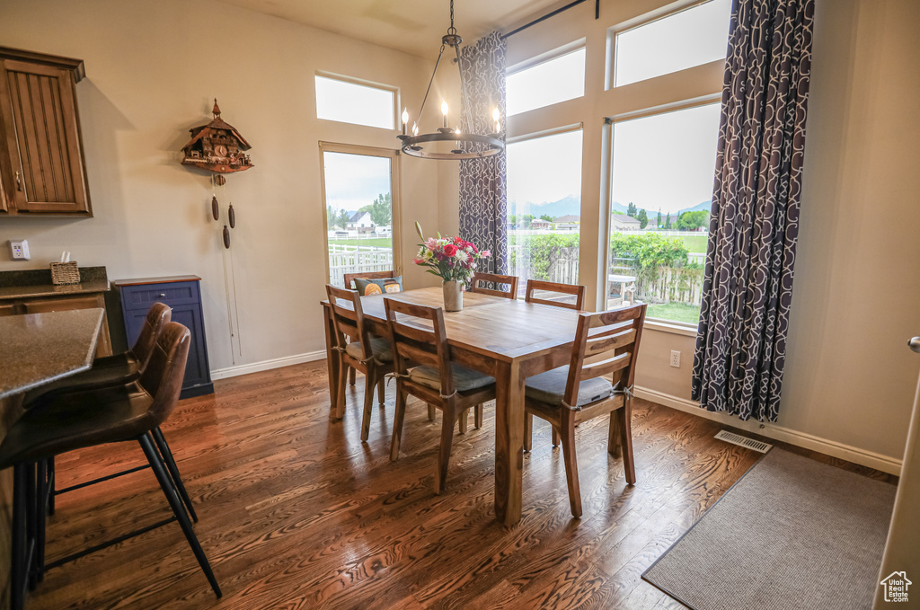 Dining area with a chandelier, dark wood-style flooring, and baseboards