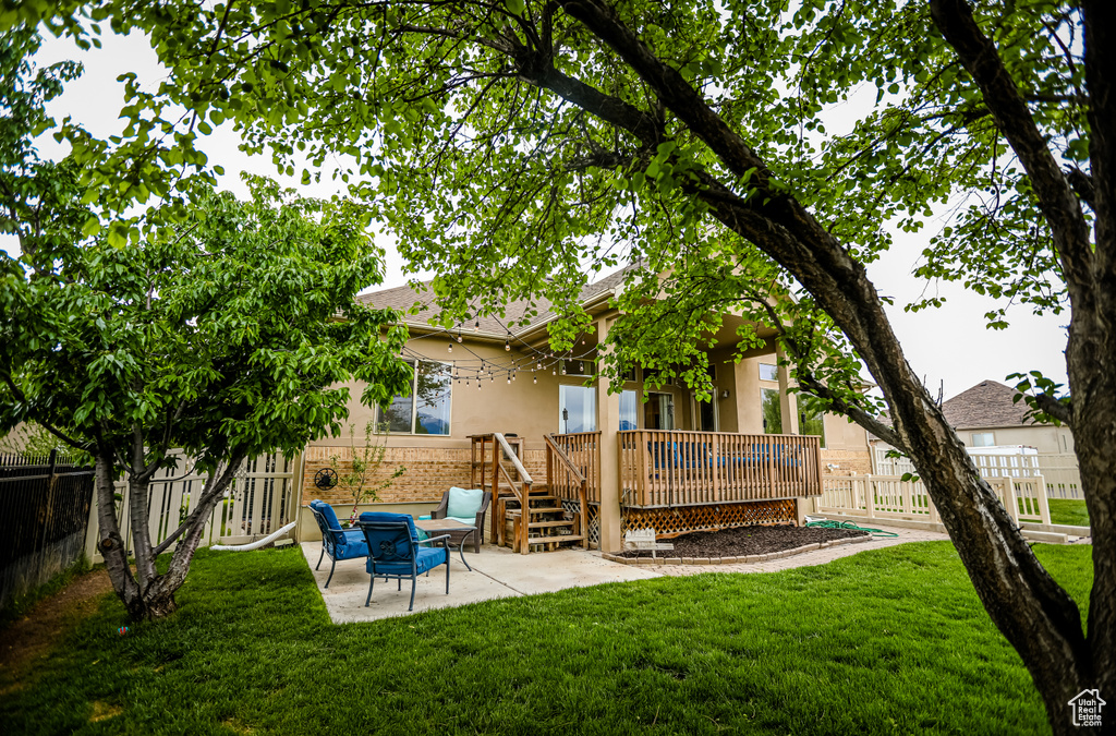 Back of property featuring a patio area, stucco siding, a wooden deck, and brick siding