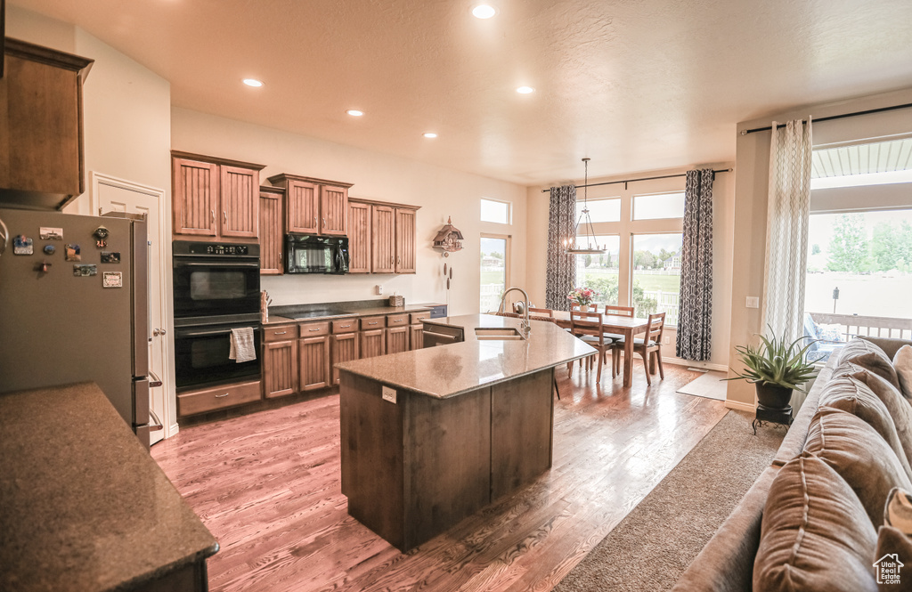Kitchen featuring black appliances, open floor plan, light wood-style flooring, recessed lighting, and healthy amount of natural light