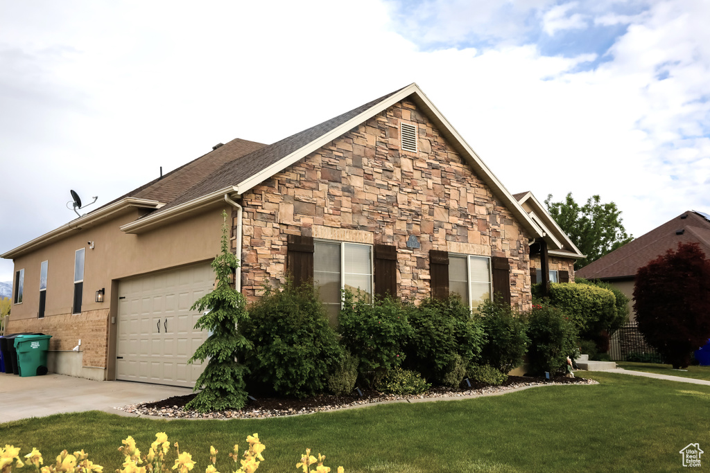 View of property exterior featuring a lawn, stone siding, a garage, and concrete driveway