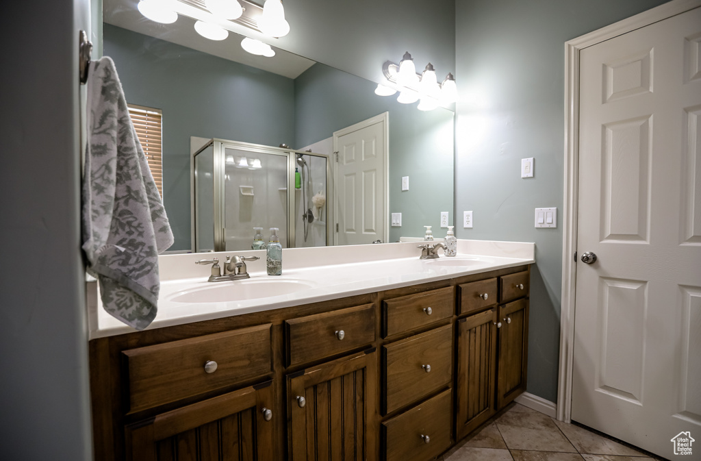 Bathroom featuring a shower stall, double vanity, and tile patterned floors