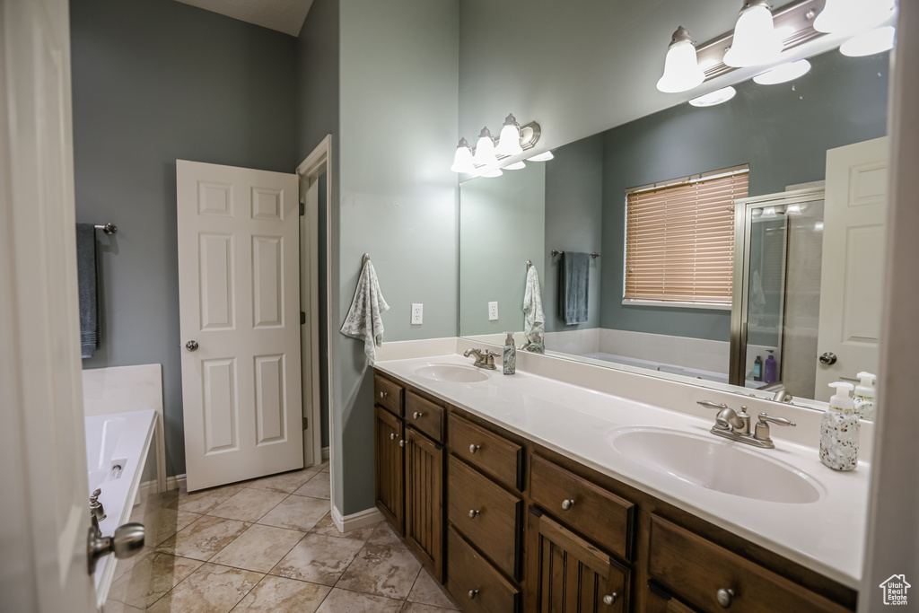 Full bathroom with double vanity, a bath, a stall shower, tile patterned floors, and baseboards