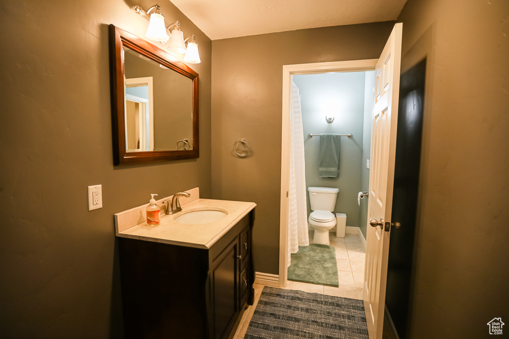 Bathroom featuring toilet, tile patterned flooring, vanity, and baseboards