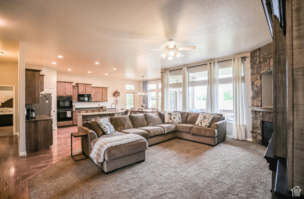 Living area with ceiling fan, a stone fireplace, recessed lighting, and a textured ceiling