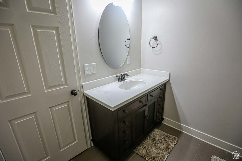 Bathroom featuring vanity, baseboards, and wood finished floors