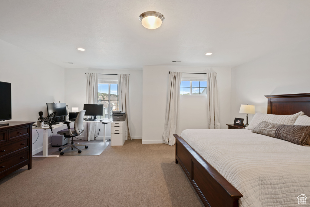 Bedroom with an office area, light carpet, recessed lighting, and baseboards