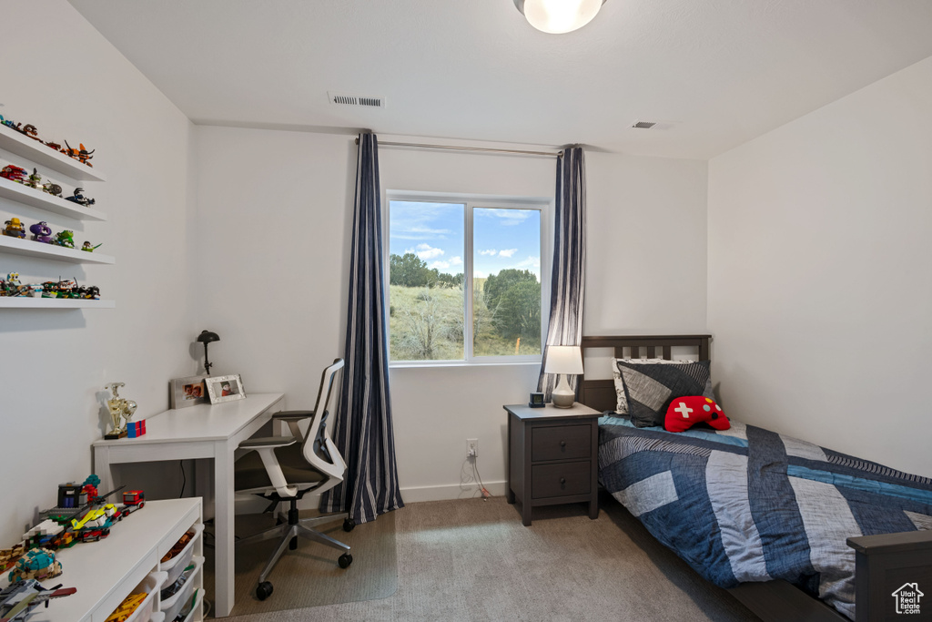 Bedroom with light carpet, an office area, and baseboards