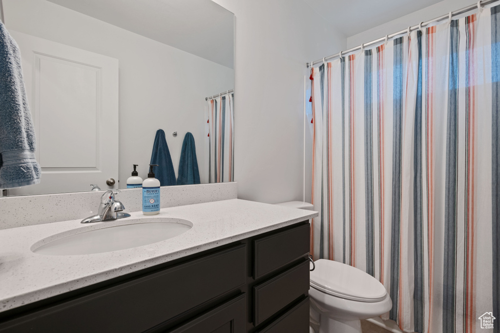 Bathroom with toilet, vanity, and curtained shower