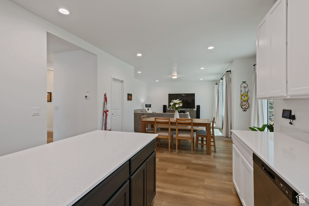 Kitchen featuring stainless steel dishwasher, white cabinetry, light wood-type flooring, recessed lighting, and light stone counters