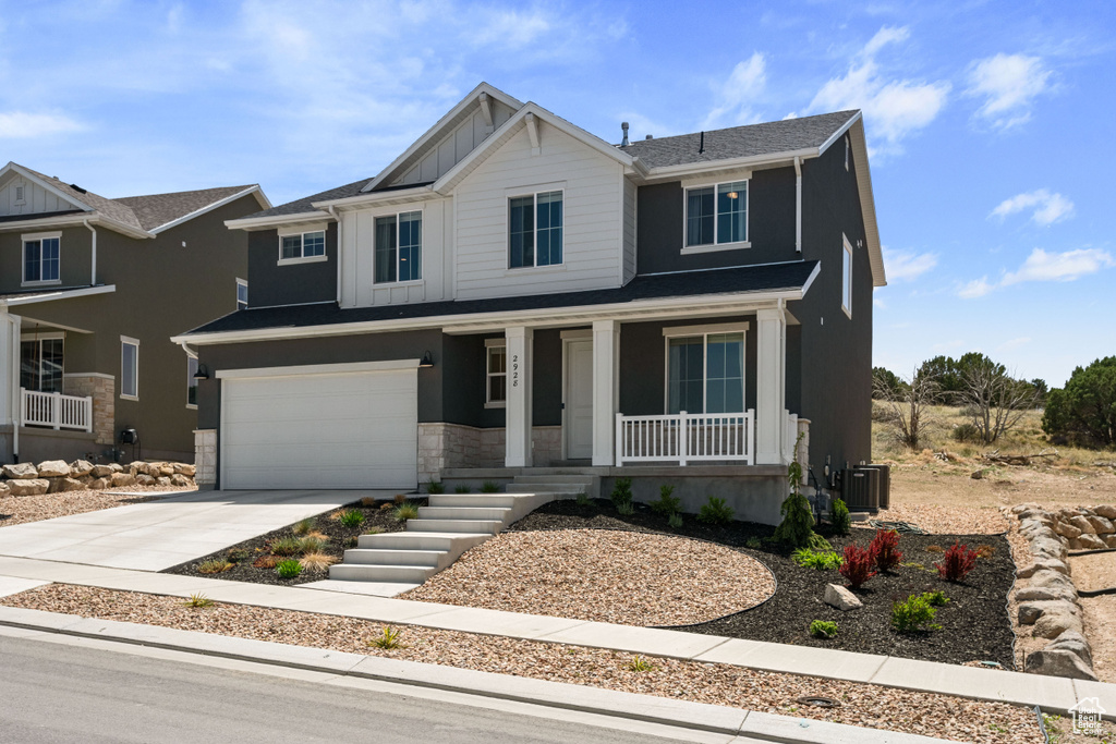 View of front of property featuring a porch, concrete driveway, cooling unit, an attached garage, and stone siding