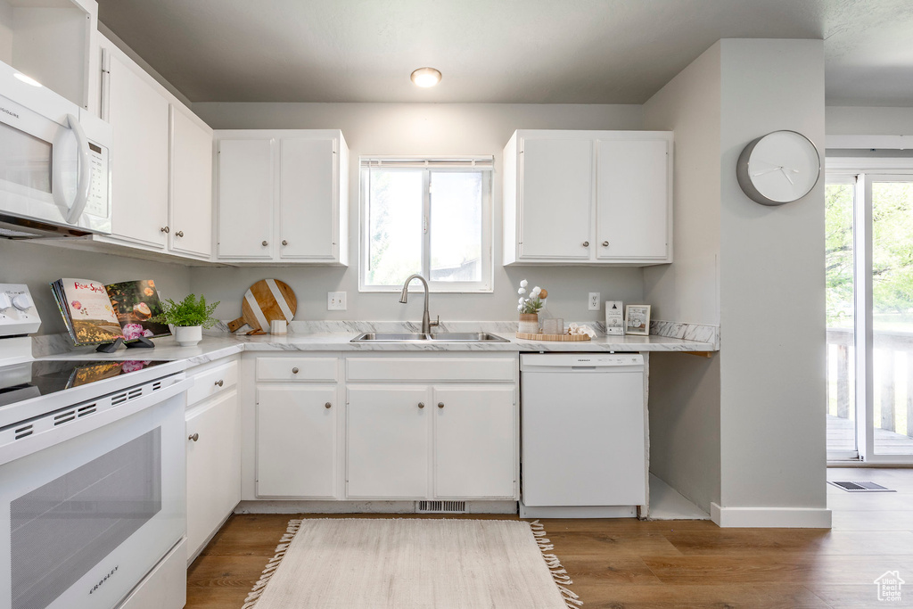 Kitchen featuring white appliances, a sink, white cabinetry, light countertops, and light wood finished floors