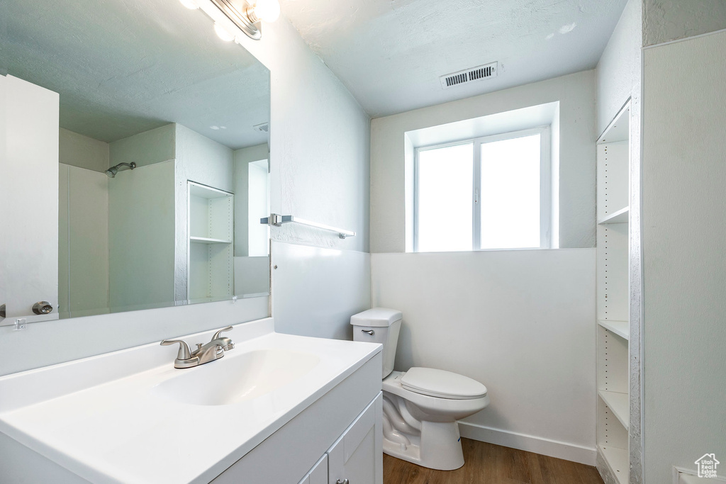 Bathroom with wood finished floors, toilet, vanity, and baseboards