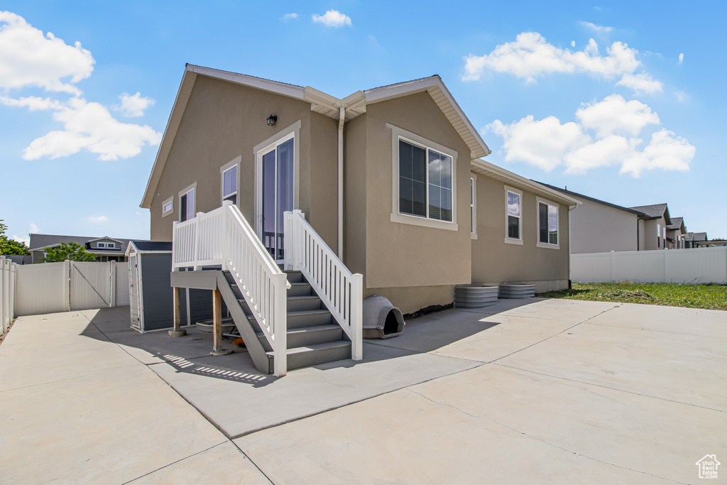 View of side of property featuring a patio area, a fenced backyard, stucco siding, and a gate