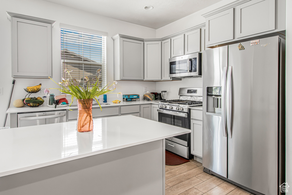 Kitchen with stainless steel appliances, gray cabinets, light countertops, light wood finished floors, and recessed lighting