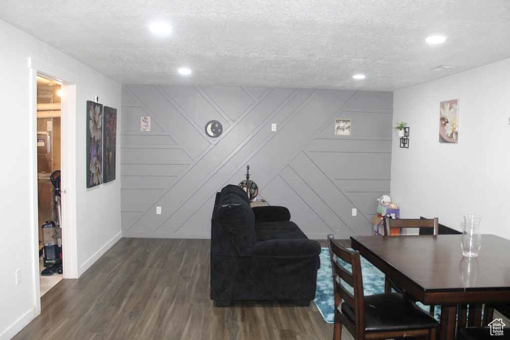 Dining room featuring a decorative wall, dark wood finished floors, a textured ceiling, baseboards, and recessed lighting