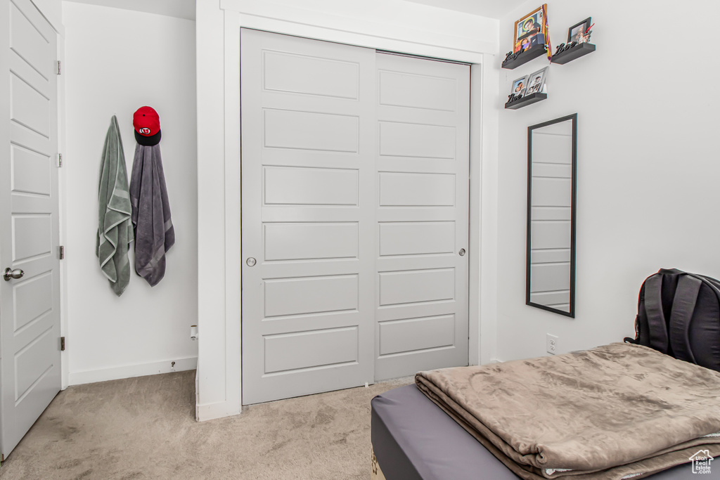 Bedroom featuring light colored carpet, a closet, and baseboards