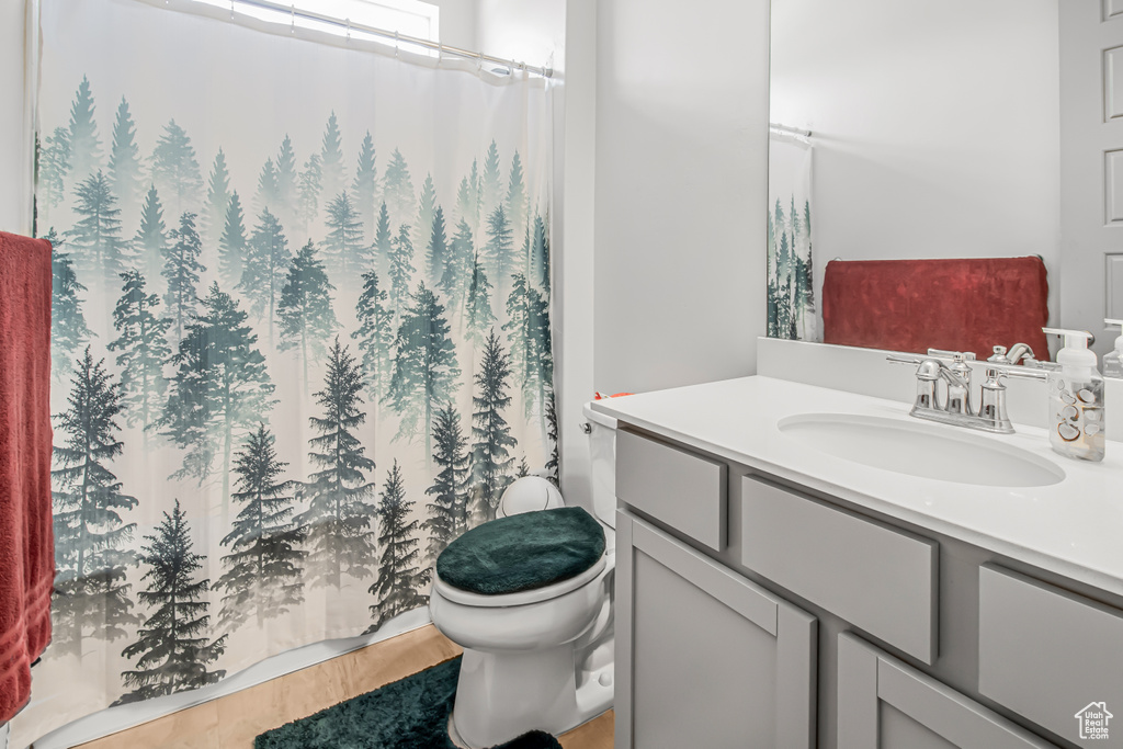 Full bathroom with vanity, toilet, wood finished floors, and curtained shower