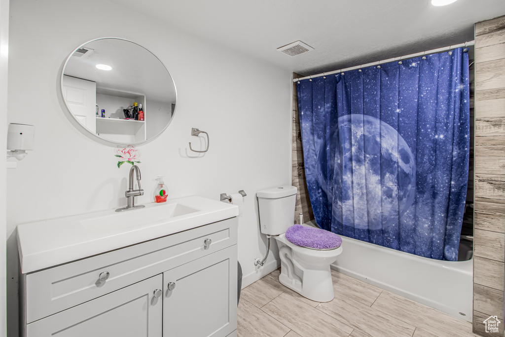 Bathroom with shower / bath combo, vanity, toilet, and wood finish floors