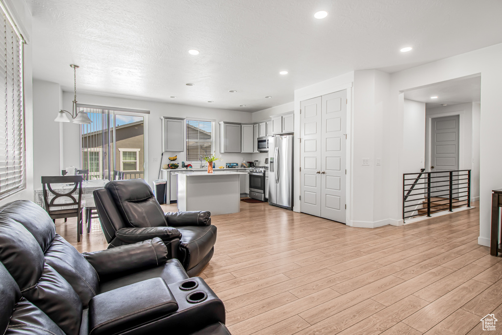 Living room with light wood-style floors, recessed lighting, and baseboards