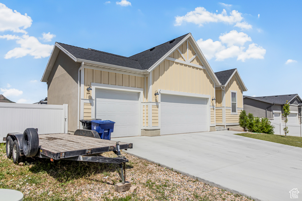 View of side of home featuring board and batten siding, a garage, and concrete driveway