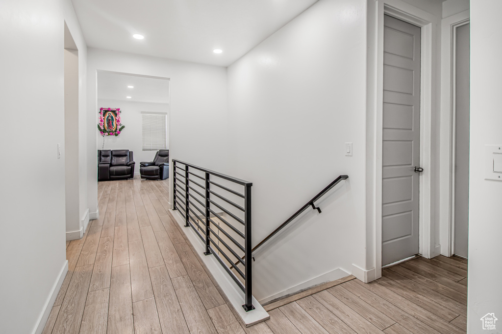 Corridor featuring an upstairs landing, light wood finished floors, recessed lighting, and baseboards