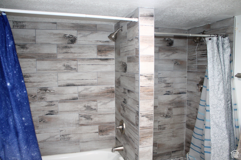 Full bath with shower / tub combo and a textured ceiling