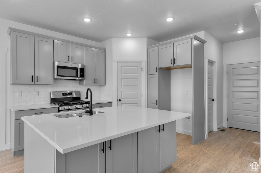 Kitchen featuring appliances with stainless steel finishes, a sink, gray cabinets, tasteful backsplash, and recessed lighting