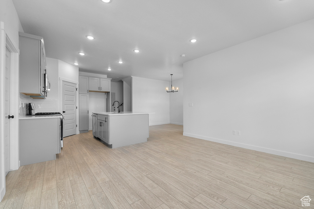 Kitchen with stainless steel appliances, a sink, a chandelier, light wood-type flooring, and recessed lighting