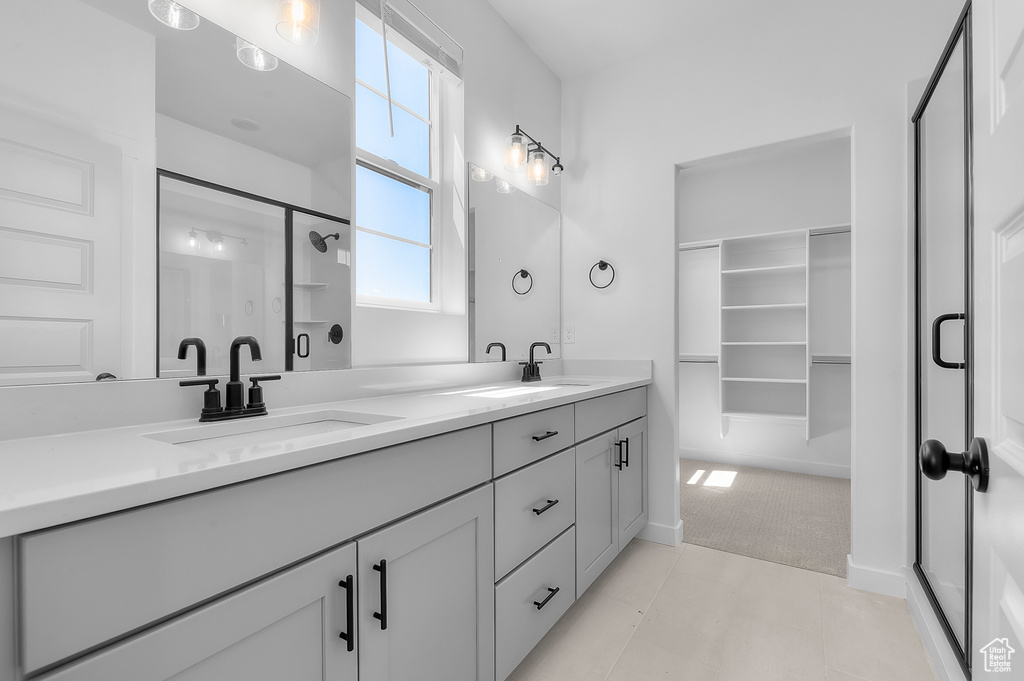 Full bathroom with a shower stall, double vanity, and a walk in closet