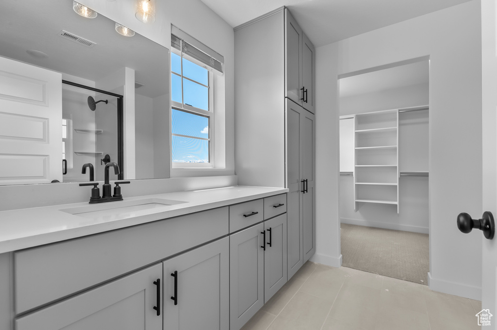 Full bath featuring a stall shower, tile patterned floors, vanity, and baseboards