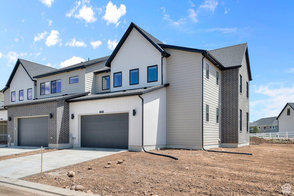 View of front of property with a garage, driveway, metal roof, and a standing seam roof