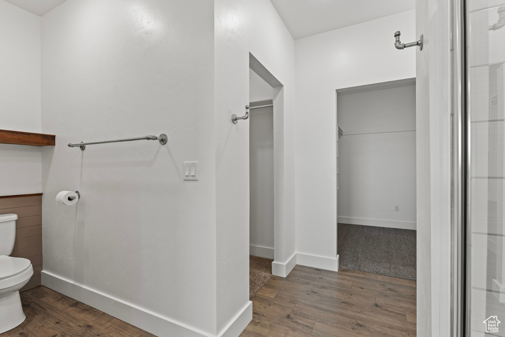 Bathroom featuring toilet, wood finished floors, and baseboards