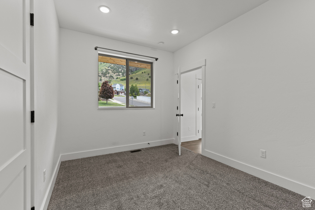 Unfurnished bedroom featuring dark carpet, baseboards, and recessed lighting