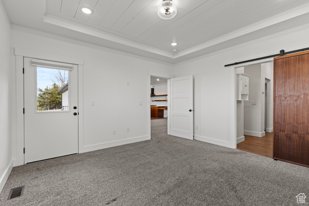 Foyer with a raised ceiling, carpet, recessed lighting, baseboards, and a barn door