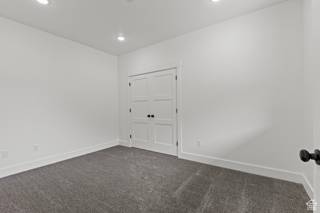 Spare room with dark colored carpet, recessed lighting, and baseboards