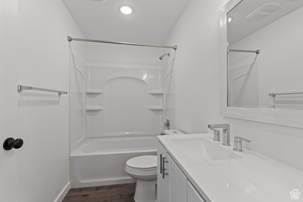 Full bath with wood finished floors, toilet, vanity,  shower combination, and baseboards