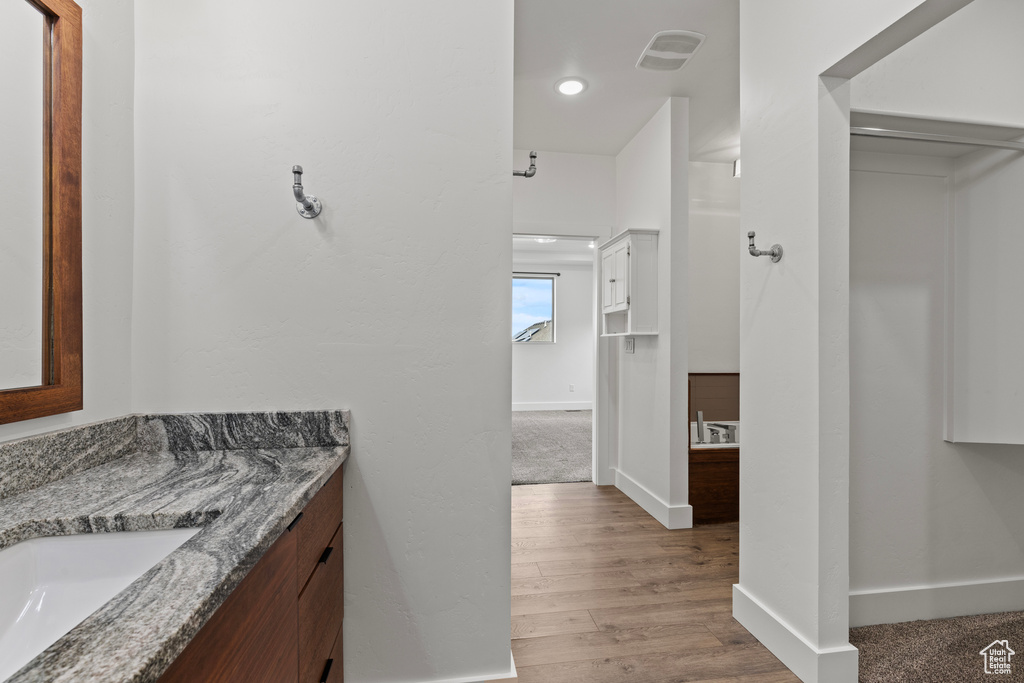 Bathroom featuring vanity, baseboards, and wood finished floors
