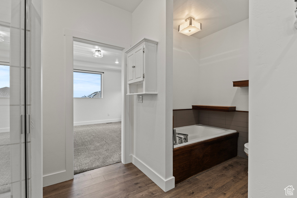 Bathroom with a bath, wood finished floors, toilet, and baseboards
