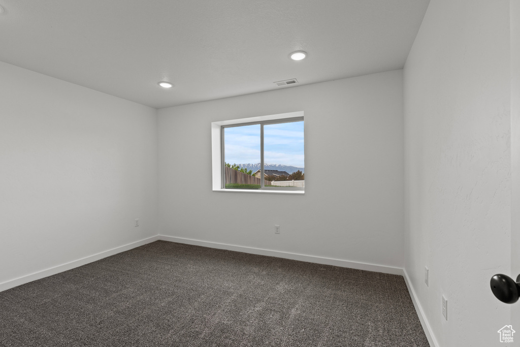 Unfurnished room featuring dark carpet, baseboards, and recessed lighting
